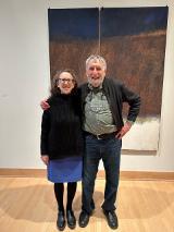 two people standing in front of a painting